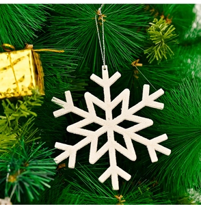 White snowflake ornament with glitter and silver string hanging on a Christmas tree