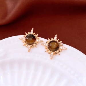 Macro shot of 18K gold plated tiger eye stone stud earrings with starburst sun pattern