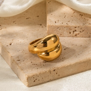 Chunky gold-plated stainless steel ring on travertine stone with silk background