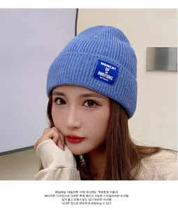 Close-up of sky blue ribbed knit beanie featuring a dark blue woven logo patch on cuff