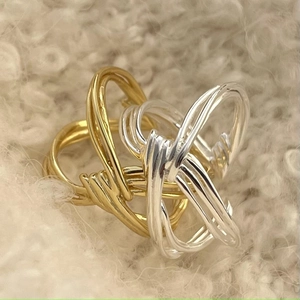 Minimalist knot crossover silver and gold ring set on a soft white plush background