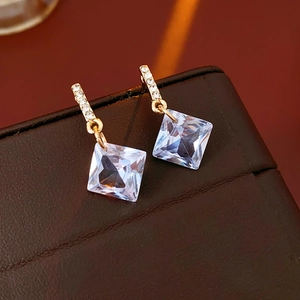Macro view of gold sparkling diamond earrings on premium brown leather jewelry box
