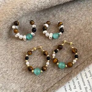 Bohemian silver and gold hoop earrings with tiger eye stones and pearls on plush fabric