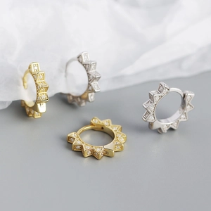 Macro detail of gear-shaped S925 silver hoop earrings with shimmering cubic zirconia