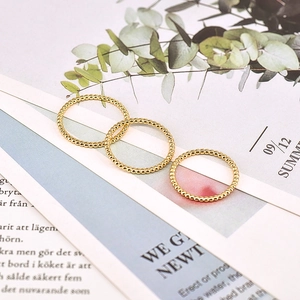 Detailed view of three 18k gold plated beaded rings stacked on a minimalist background