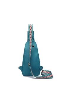Detail of teal crossbody bag featuring ethnic geometric strap and metal earphone port