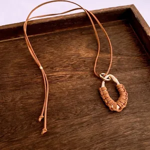 Collier rétro goutte évidée avec cordon en daim marron sur plateau en bois