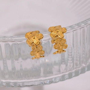 Macro di eleganti ear cuff a fiore dorati su vetro, con focus sulla trama metallica