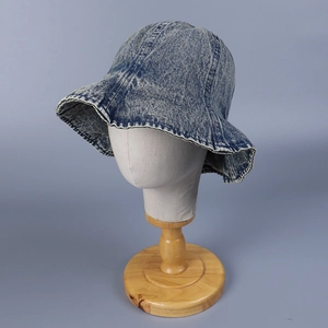 Chapeau bob en jean délavé avec bord à volants présenté sur un support minimaliste gris