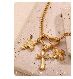 Detail of 18K gold-plated necklace featuring a heart clasp and three cross pendants