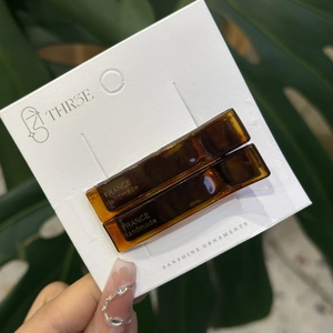 Close-up of amber acetate hair clips with gold handmade text on brand packaging card