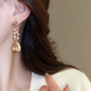 Close-up of gold drop earrings with champagne crystals worn by a female model