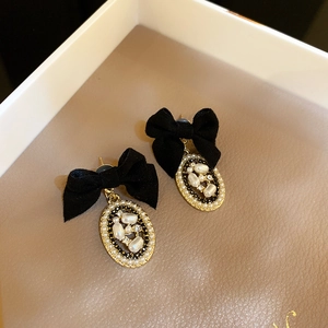 Close-up of velvet bow earrings with faux pearls and rhinestones on a gold frame