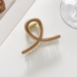 Close-up of beige and brown striped plastic hair claw clip with golden metal spring