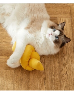 Gato jugando con juguete de pana amarilla sobre suelo de madera en ambiente acogedor