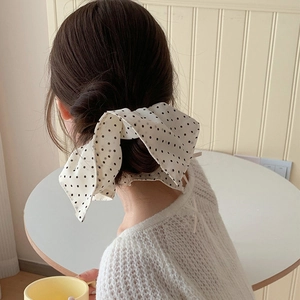 Detail of oversized cream bow hair scrunchie with black polka dots on a low ponytail