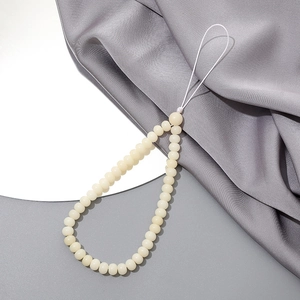 Close-up of cream crystal agate beaded phone strap with round polished beads on silk fabric