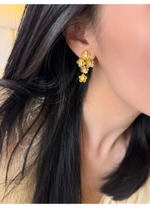 Macro shot of vintage style gold flower drop earrings with white zircon crystals on model