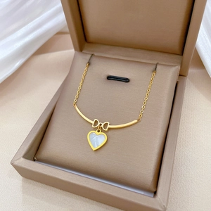 Titanium steel gold necklace with bow and white heart pendant on silk in a jewelry box