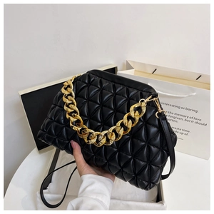 Detail of a black quilted shell handbag with a bold gold chain and leather strap