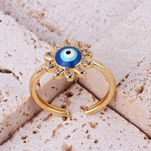 Close-up of golden evil eye ring with blue enamel and white zircon petals on stone