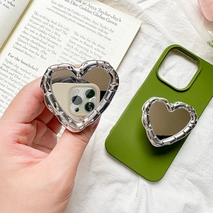 Creative heart mirror phone stand with silver frame on a grass green silicone case