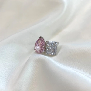 Macro shot of silver ring with pink pear-cut and white rectangular stones on white silk