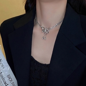 Elegant silver bow earrings with sparkling rhinestones worn by a model in a black suit