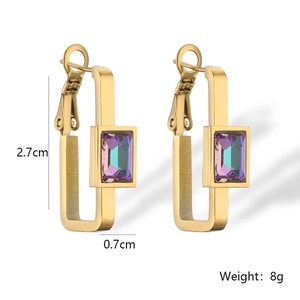 Detail view of gold geometric earrings with purple-green zircons and 2.7cm size specs