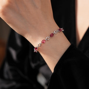 Close-up of silver chain bracelet with oval red zircons on a female wrist