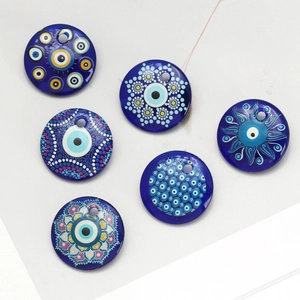 Detail of six assorted 30mm blue glass evil eye charms with varied mandala designs