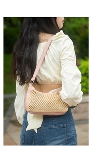 Outdoor model shot of a pink leather and woven straw underarm bag for summer style
