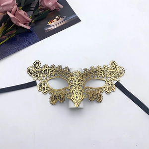 Detailed view of a gold lace masquerade mask with black silk ribbon on a white background