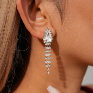 Macro shot of silver teardrop tassel earrings with sparkling rhinestones on model