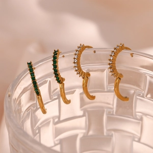 Golden mini huggie hoops with green and white zircon crystals on a glass rim