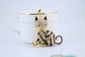 Detail of a sparkling black enamel lucky cat keychain with crystal rhinestones on white base