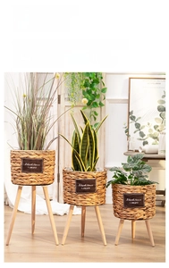 Close-up of woven rattan flower pots with wooden tripod stands and natural leather labels