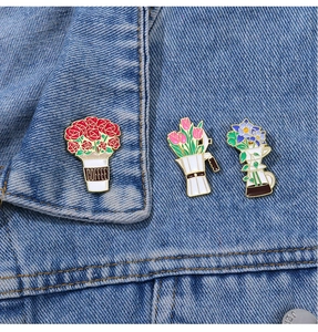 Detailed enamel pins of floral coffee cups and pots on blue denim jacket fabric