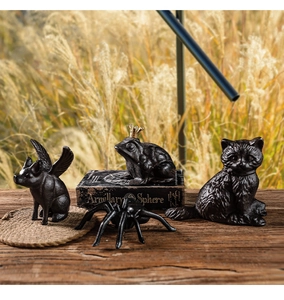 Set of four rustic cast iron animal figurines including a cat and a crowned frog on wood