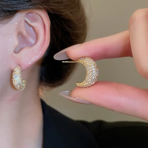 Close-up of gold crescent moon earrings with micro-paved white zircon stones