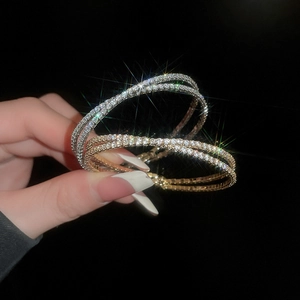 Gros plan de bracelets croisés en zircon étincelant finitions dorée et argentée avec strass