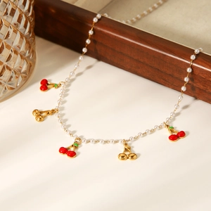 Gros plan du collier de perles avec des pendentifs cerise rouge et des détails dorés