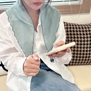 Light blue-green chiffon triangle scarf with navy blue edges worn by a model in casual setting