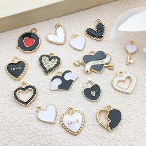Detailed flat lay of heart and wing alloy charms with black and white enamel finishes