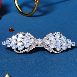 Macro detail of silver bow hair clip with sparkling cubic zirconia on blue background