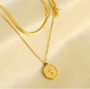 Close-up of golden double-layer necklace with snake chain and engraved hexagram pendant