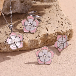 Detailed set of pink floral necklace, earrings and ring on natural stone background