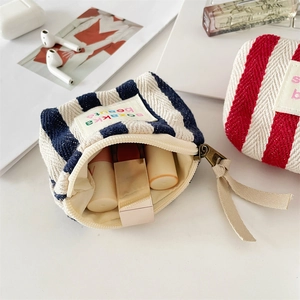 Detailed shot of striped canvas makeup pouches with long drawstrings and embroidery