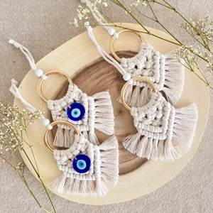 Handmade macrame evil eye pendants with cotton ropes and golden rings on wood base