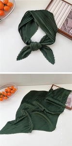 Detail of dark green pleated scarf showing fine texture and elegant knotted style